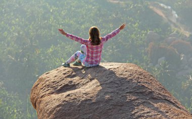 Genç bir kız bir lotus poz güneş tebrik gündoğumu veya günbatımı oturma bir dağın tepesinde bir arka plan üzerinde veya büyük bir kayanın üzerinde. Hampi doğada meditasyon. Vijayanagar, İstanbul, unesco.