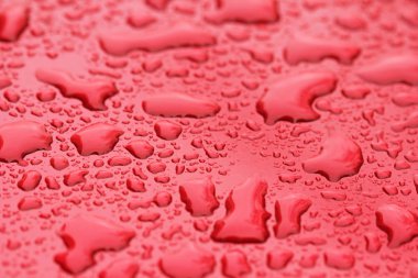 Yağmur veya su damla kırmızı arabanın kaputu bırakın. Arabanın yüzeyinde veya demir yüzey akışı üzerinde yağmur düşer. Arka plan ve su doku tasarımı için.