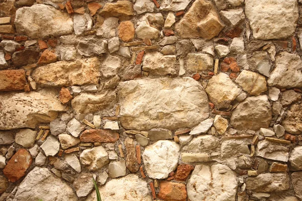 Background of brown, beige and gray stones. The old wall of stones. Ancient ruins. Beige background of stones. The island of Sicily, Italy.