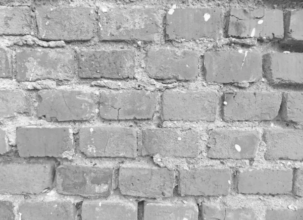 Die alte Mauer aus weißen und grauen Ziegelsteinen bröckelte und riss. grau a — Stockfoto