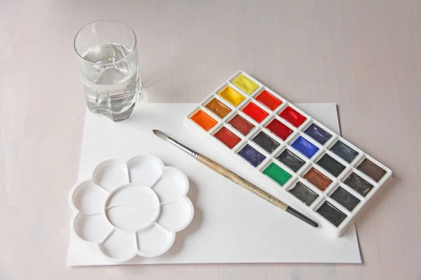 Akvarellekkel, ecsetek, paletta, fehér papírlap, és egy üveg — Stock Fotó