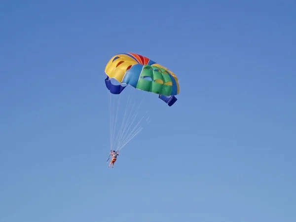 Foto tirada no verão. O homem está voando em um parac circular colorido — Fotografia de Stock