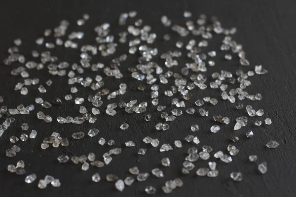 Diamantes espalhados sobre um fundo preto. Diamantes brutos e minin — Fotografia de Stock