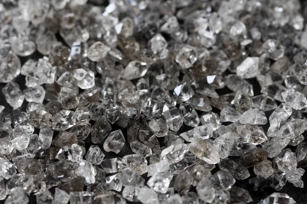 Scattered diamonds on a black background. Raw diamonds and minin