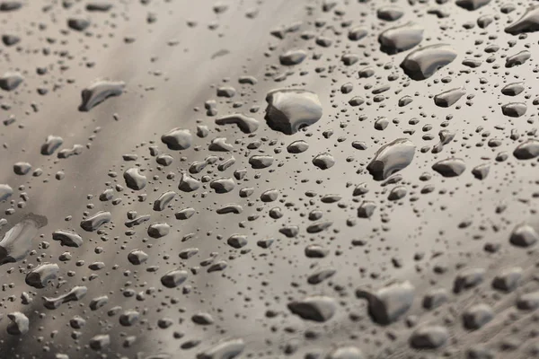 Druppels regen of water vallen op de motorkap van de auto. Regendruppels o — Stockfoto