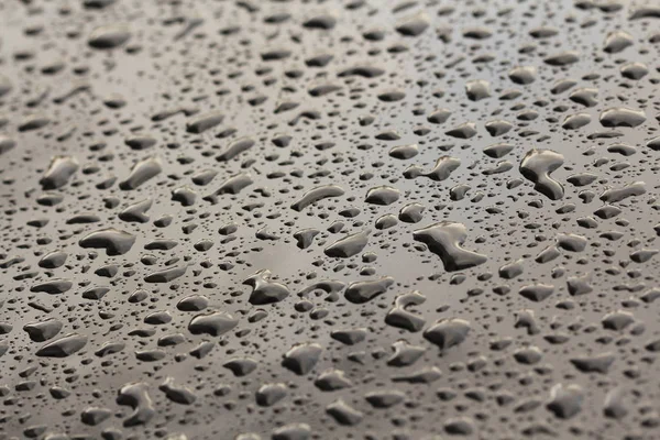 Druppels regen of water vallen op de motorkap van de auto. Regendruppels o — Stockfoto