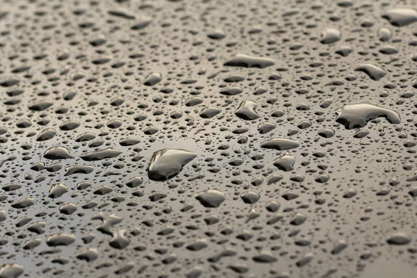 Druppels regen of water vallen op de motorkap van de auto. Regendruppels o — Stockfoto