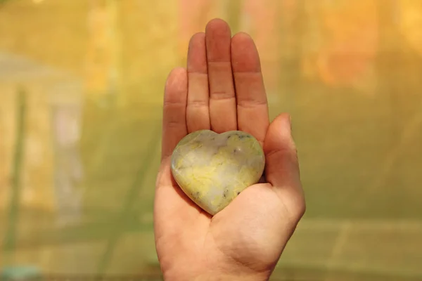 Рука держит сердце из натурального камня желтый жадеит. Хеа — стоковое фото