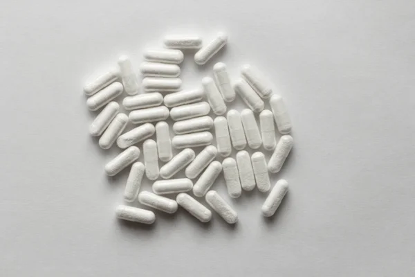 White Transparent Capsules or Tablets on the White Background. M