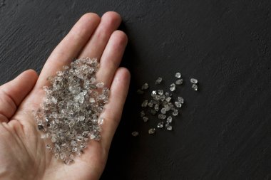 Raw natural diamonds, graphite quartz are in the hand. A scatter clipart