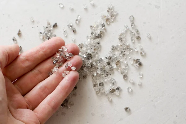 Raw natural diamonds, graphite quartz are in the hand. A scatter