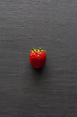 Bir kırmızı güzel çilek yakın çekim, siyah koyu beton üzerinde 