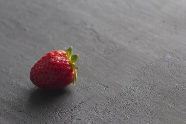 Bir kırmızı güzel çilek yakın çekim, siyah koyu beton üzerinde 