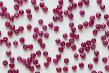 Yakut taşları beyaz bir masanın üzerinde, beyaz bir arka plan da yatıyor. Doğal st