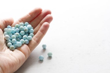 Larimar taşı elinde yatıyor. Beyaz üzerinde doğal taş larimar