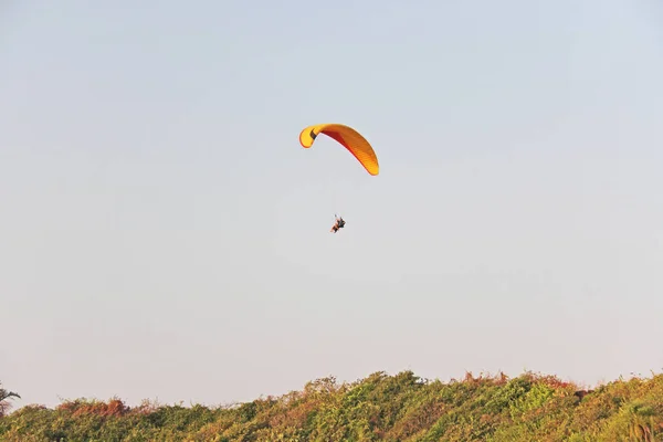 A paraglider against the blue sky. A bright paraglider flies in — Stock Photo, Image