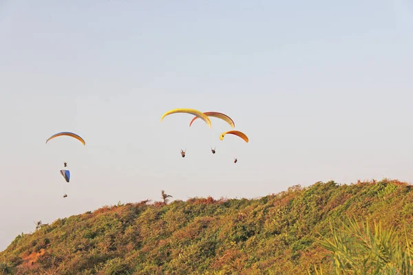 Paragliders against the blue sky. Bright paragliders fly in the — Stock Photo, Image