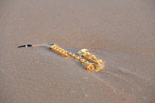 Den gyllene Altsaxofonen ligger på sanden eller på stranden. Musi — Stockfoto