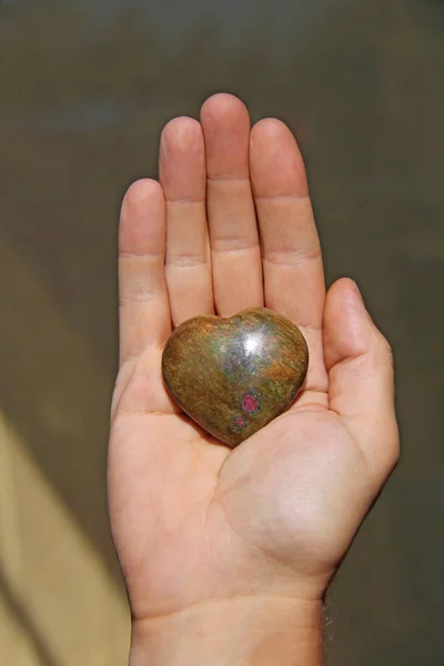 De hand houdt het hart van de natuursteen van de iotsit. H — Stockfoto