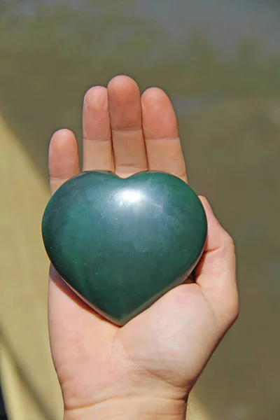 The hand holds the heart from natural stone green jade. Heart in — Stock Photo, Image