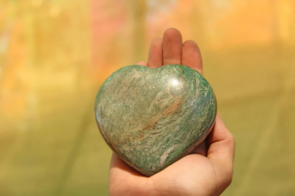 Ręka trzyma serce z naturalnego marmuru kamień lub zielony AV — Zdjęcie stockowe