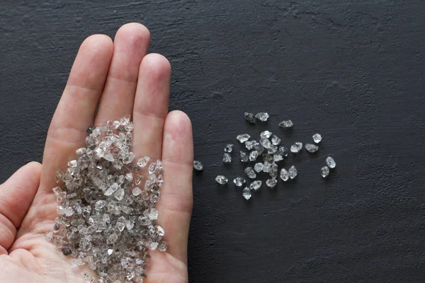 Raw natural diamonds, graphite quartz are in the hand. A scatter