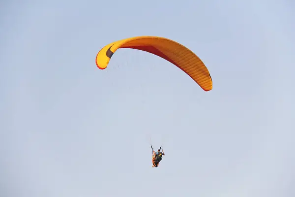 Um parapente contra o céu azul. Um parapente brilhante voa dentro — Fotografia de Stock