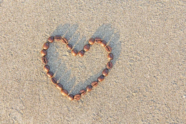 Hjärtat av kaffe. Korn av kaffe läggs ut på sand i fo — Stockfoto