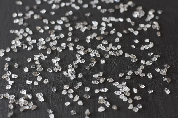 Diamantes espalhados sobre um fundo preto. Diamantes brutos e minin — Fotografia de Stock