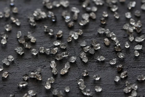 Scattered diamonds on a black background. Raw diamonds and minin