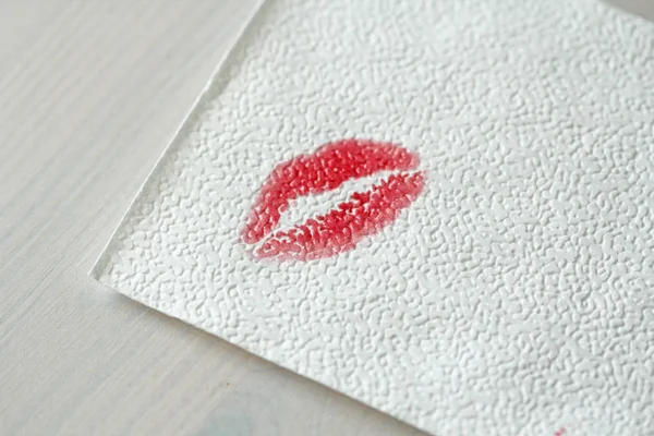 Impresión o un rastro de un beso, lápiz labial rojo en una servilleta blanca . — Foto de Stock