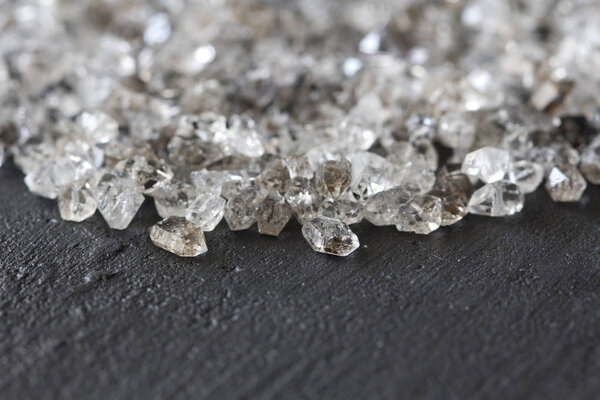 Разбросанные бриллианты на черном фоне. Сырые алмазы и минин
