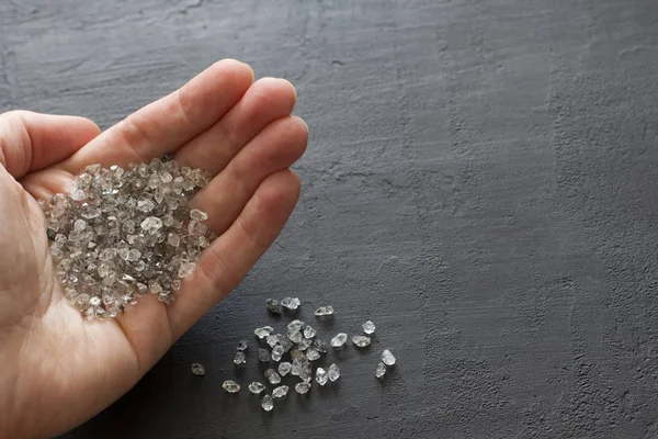 Raw natural diamonds, graphite quartz are in the hand. A scatter