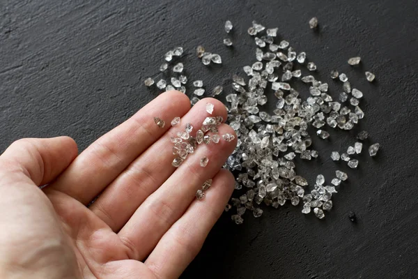 Raw natural diamonds, graphite quartz are in the hand. A scatter