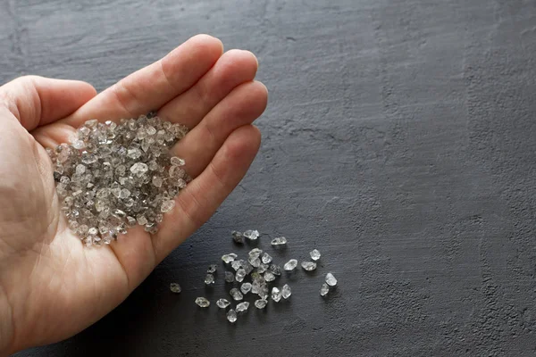 Raw natural diamonds, graphite quartz are in the hand. A scatter