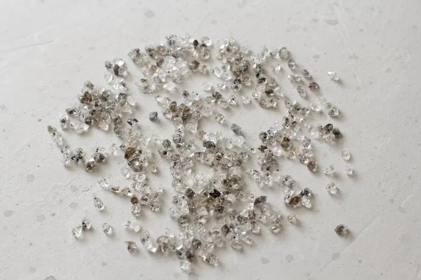 Scattered diamonds on a grey background. Raw diamonds and mining
