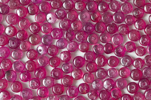 Ruby stones lie on a white table, a white background. Natural st