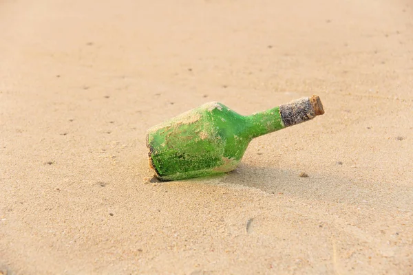 Green glass bottle with a message inside on the seashore on the — Stock Photo, Image