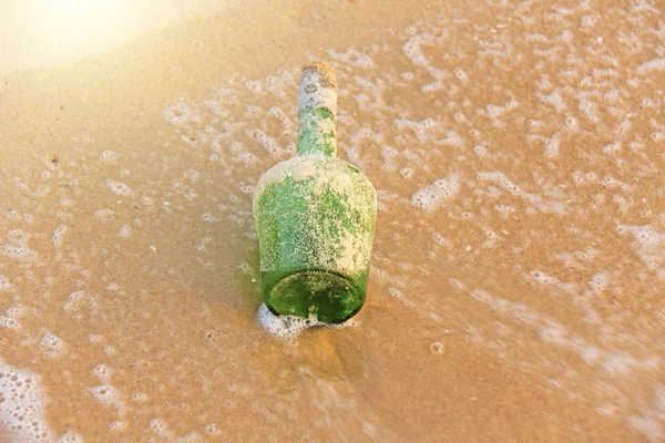 Botella de vidrio verde con un mensaje dentro en la orilla del mar en el —  Fotos de Stock
