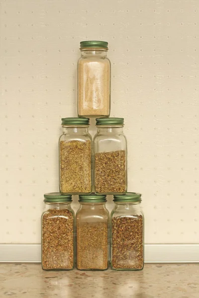 Μπαχαρικά σε γυάλινα βάζα σε ανοιχτόχρωμο φόντο στην κουζίνα. Βασιλικό — Φωτογραφία Αρχείου