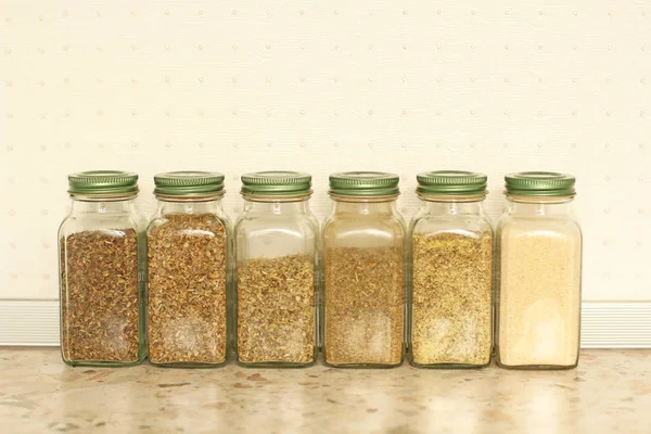 Especias en frascos de vidrio sobre un fondo claro en la cocina. Basilio. — Foto de Stock