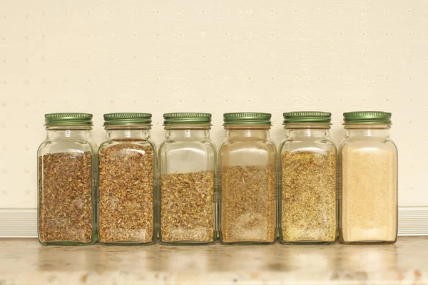 Especias en frascos de vidrio sobre un fondo claro en la cocina. Basilio. — Foto de Stock