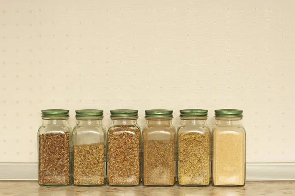 Spices in glass jars on a light background in the kitchen. Basil — Stock Photo, Image