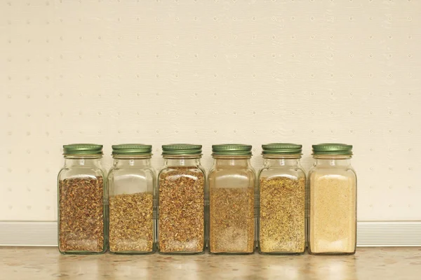 Spices in glass jars on a light background in the kitchen. Basil — Stock Photo, Image