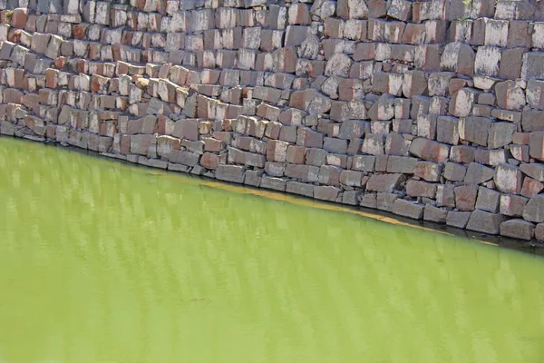 Abstrakter geometrischer Hintergrund mit grünem Wasser und grauem Ziegelstein — Stockfoto
