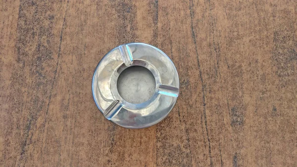 Cenicero vacío de metal de acero sobre una mesa beige. Vista desde arriba — Foto de Stock