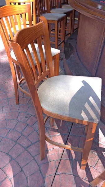 High wooden bar stools and a bar counter in the street