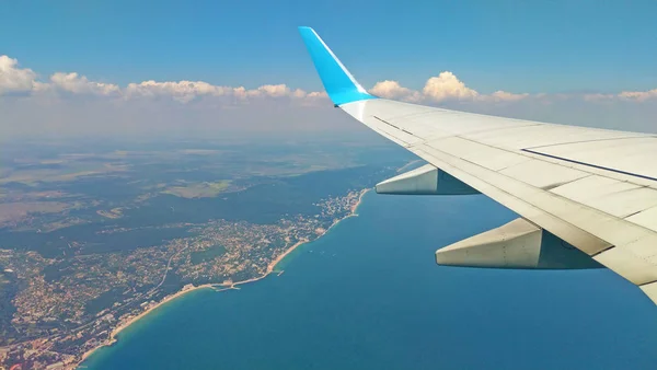 Flygplansvinge utsikt ut genom fönstret på molnigt himlen jorden — Stockfoto