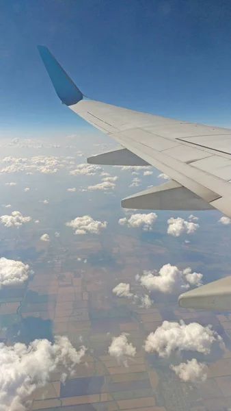 Flygplansvinge utsikt ut genom fönstret på molnigt himlen bakgrunds — Stockfoto