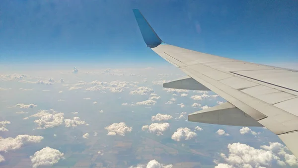 Flygplansvinge utsikt ut genom fönstret på molnigt himlen bakgrunds — Stockfoto